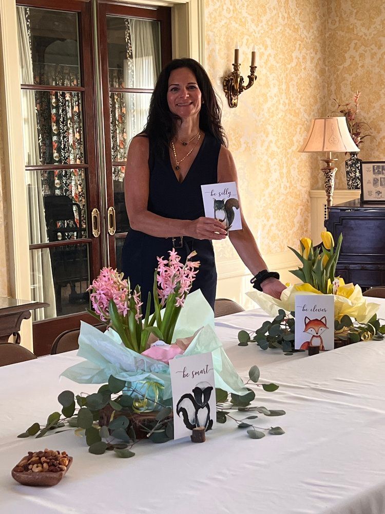A woman is standing in front of a table with flowers and cards on it.