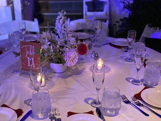 A table set for a wedding reception with plates , glasses , candles and flowers.