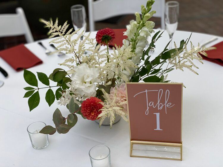 A table with a vase of flowers and a table number on it.