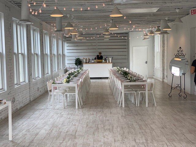 A large room with tables and chairs set up for a wedding reception.