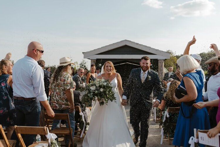 A bride and groom are walking down the aisle at their wedding.
