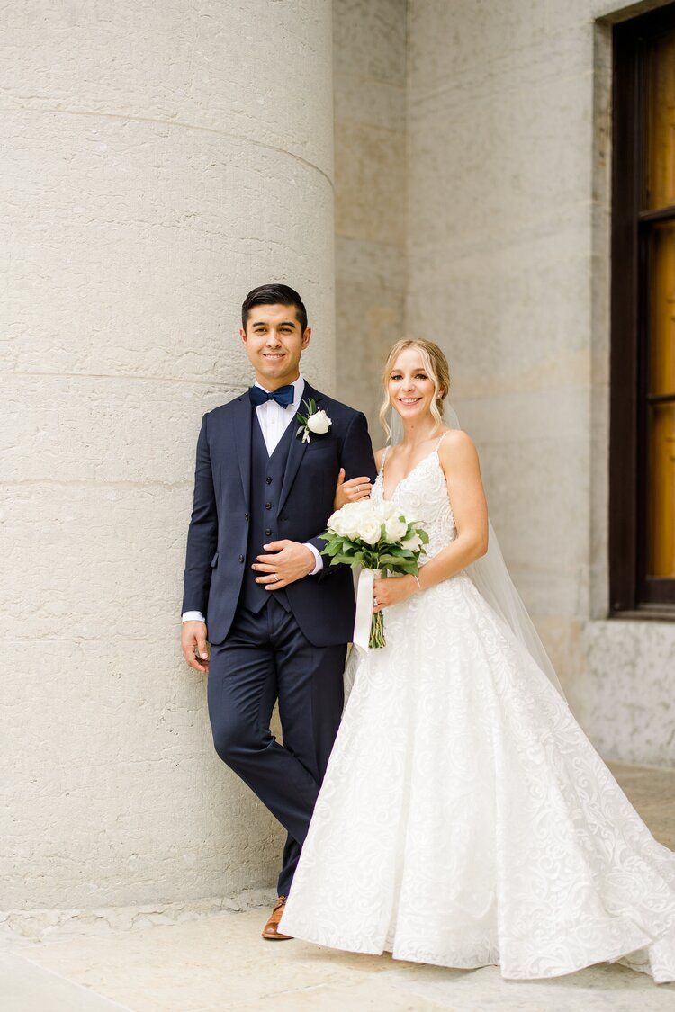 A bride and groom are posing for a picture in front of a building.