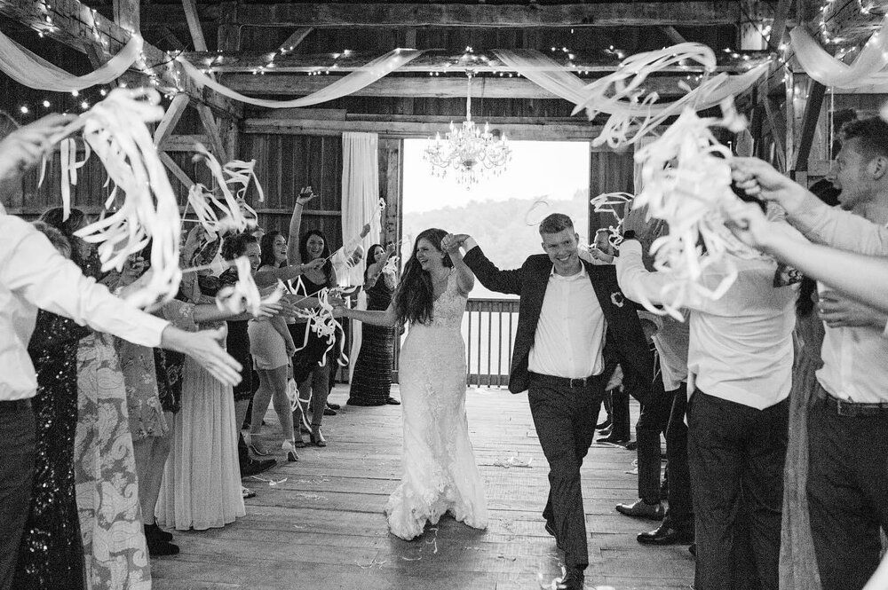 A bride and groom are walking through a crowd of people at their wedding reception.