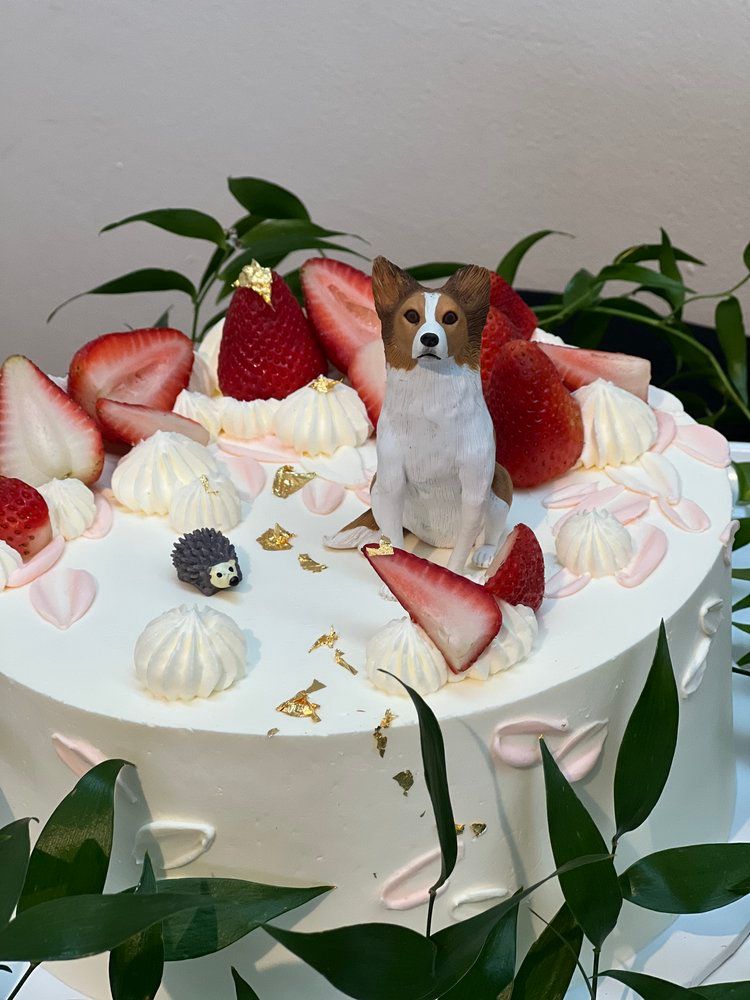 A cake with strawberries and a dog figurine on top