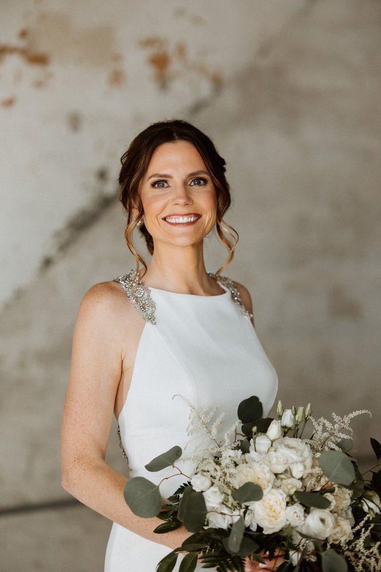 The bride is wearing a white dress and holding a bouquet of flowers.