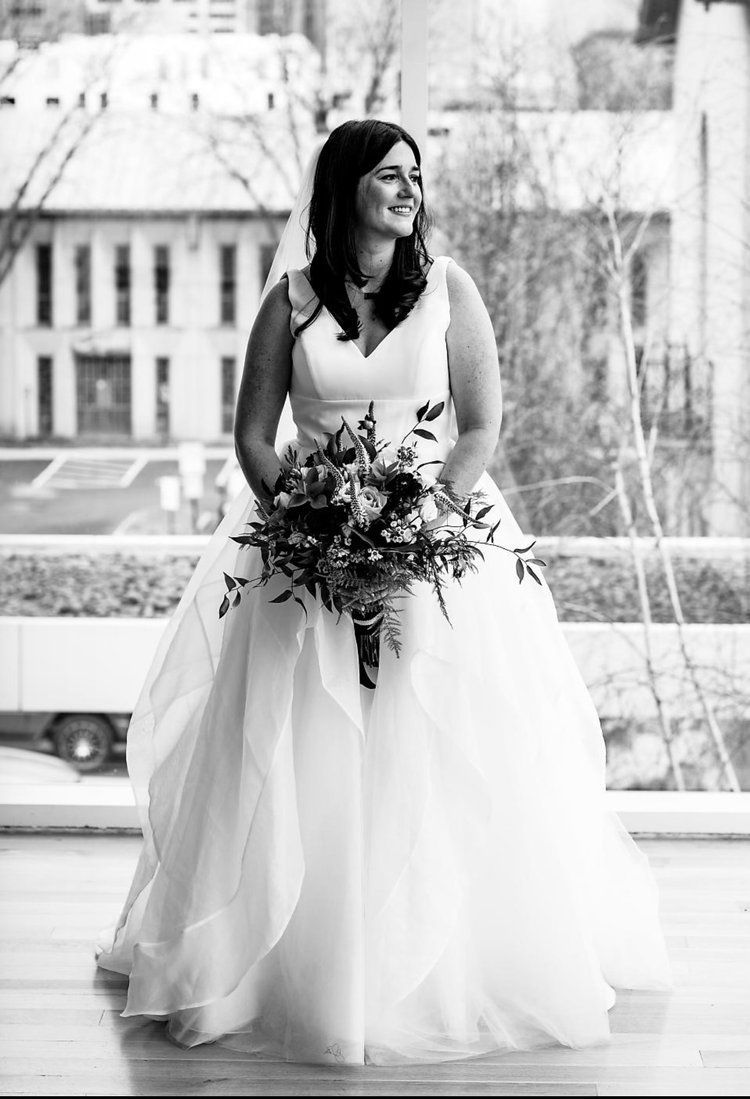 A black and white photo of a bride in a wedding dress holding a bouquet of flowers.