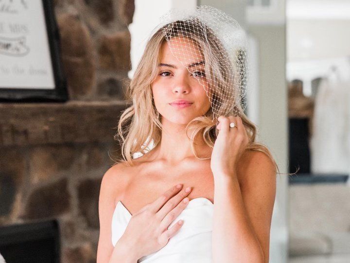 A woman in a white dress and veil is standing in front of a fireplace.