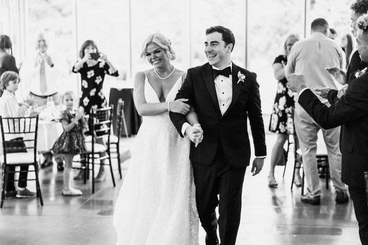 A bride and groom are walking down the aisle at their wedding reception.