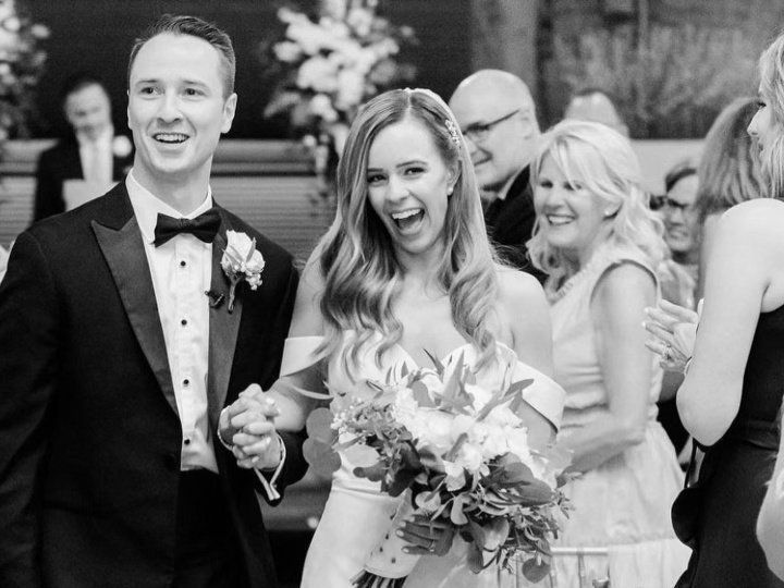 A black and white photo of a bride and groom walking down the aisle.