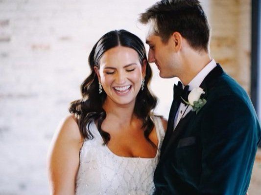 A bride and groom are looking at each other and smiling.
