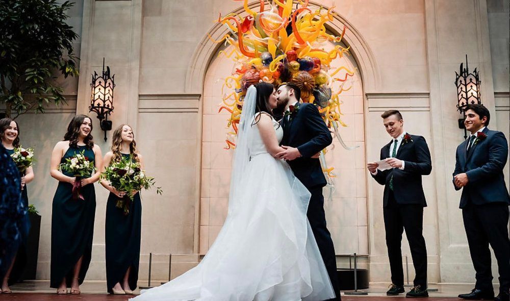 A bride and groom kissing in front of their wedding party.