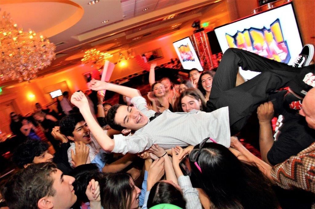 A man is being lifted in the air by a crowd at a party