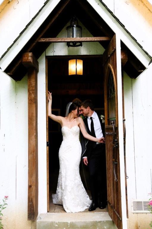 A bride and groom kissing in the doorway of a church