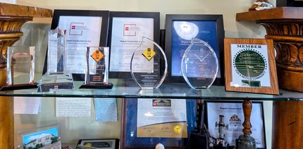 Shelves of framed certificates and glass awards displayed in a room