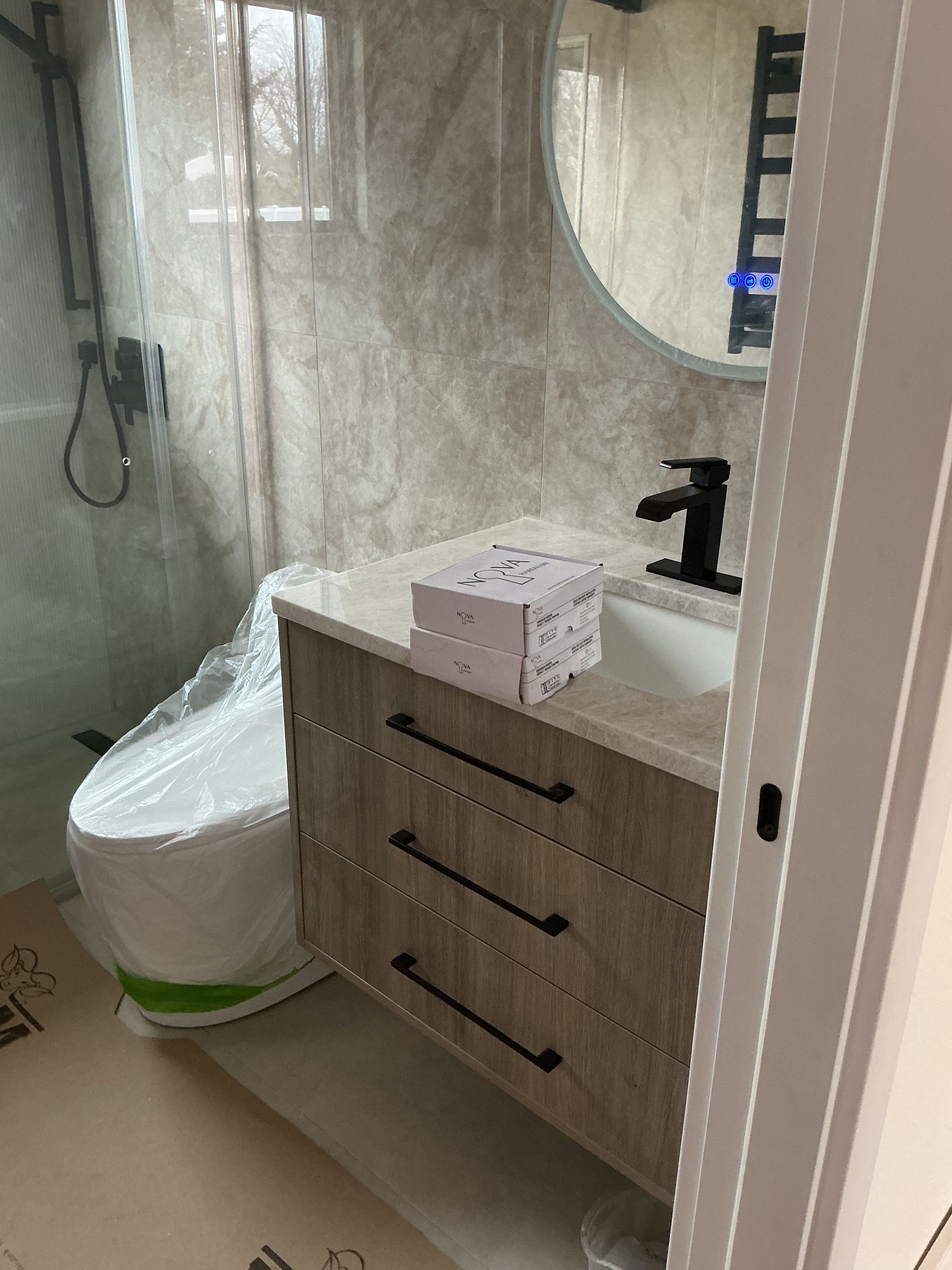 Small bathroom vanity with black faucet, tissue box, and toilet beside a shower.