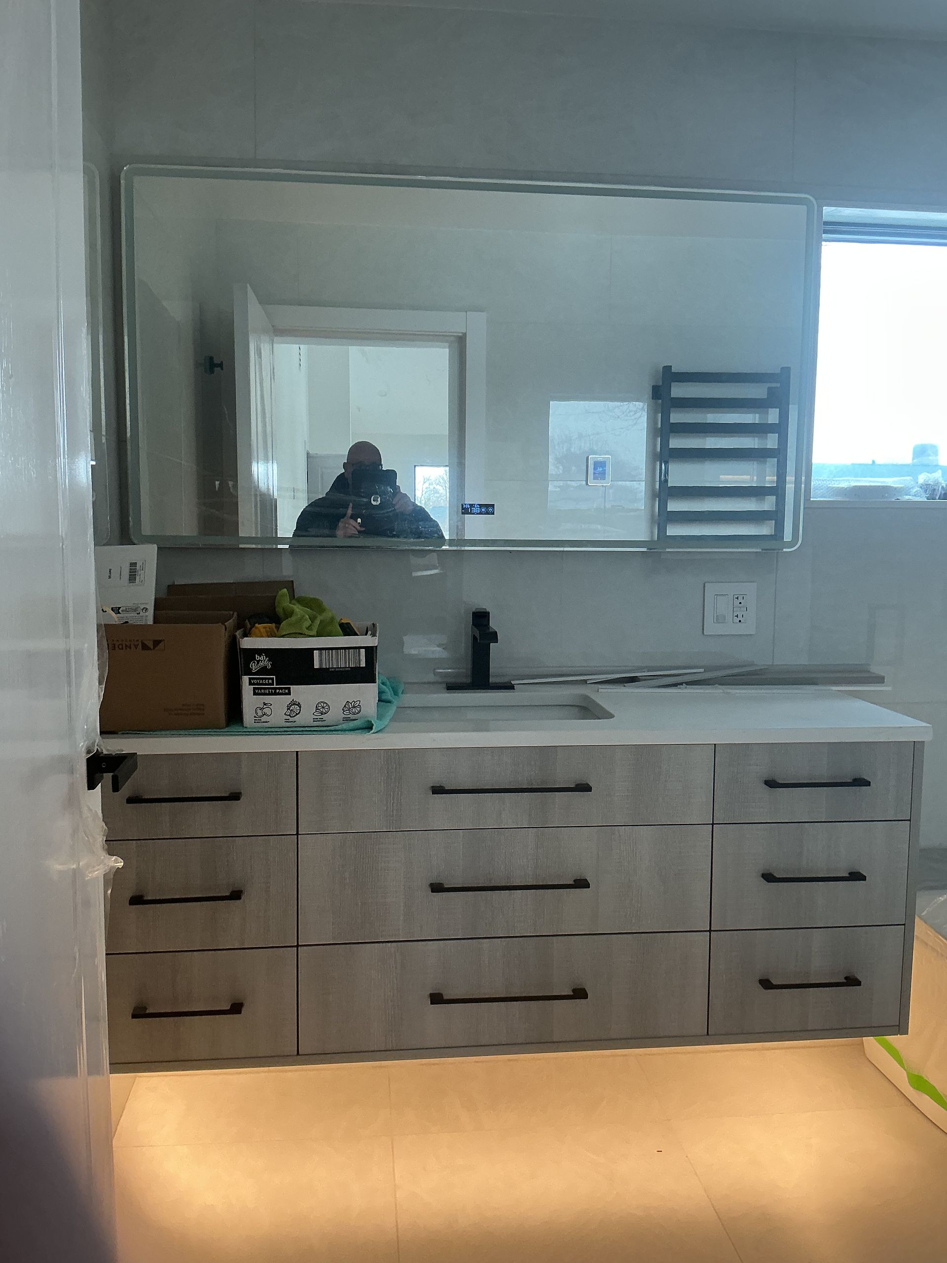 Bathroom vanity with double sink, large mirror, and warm floor lighting