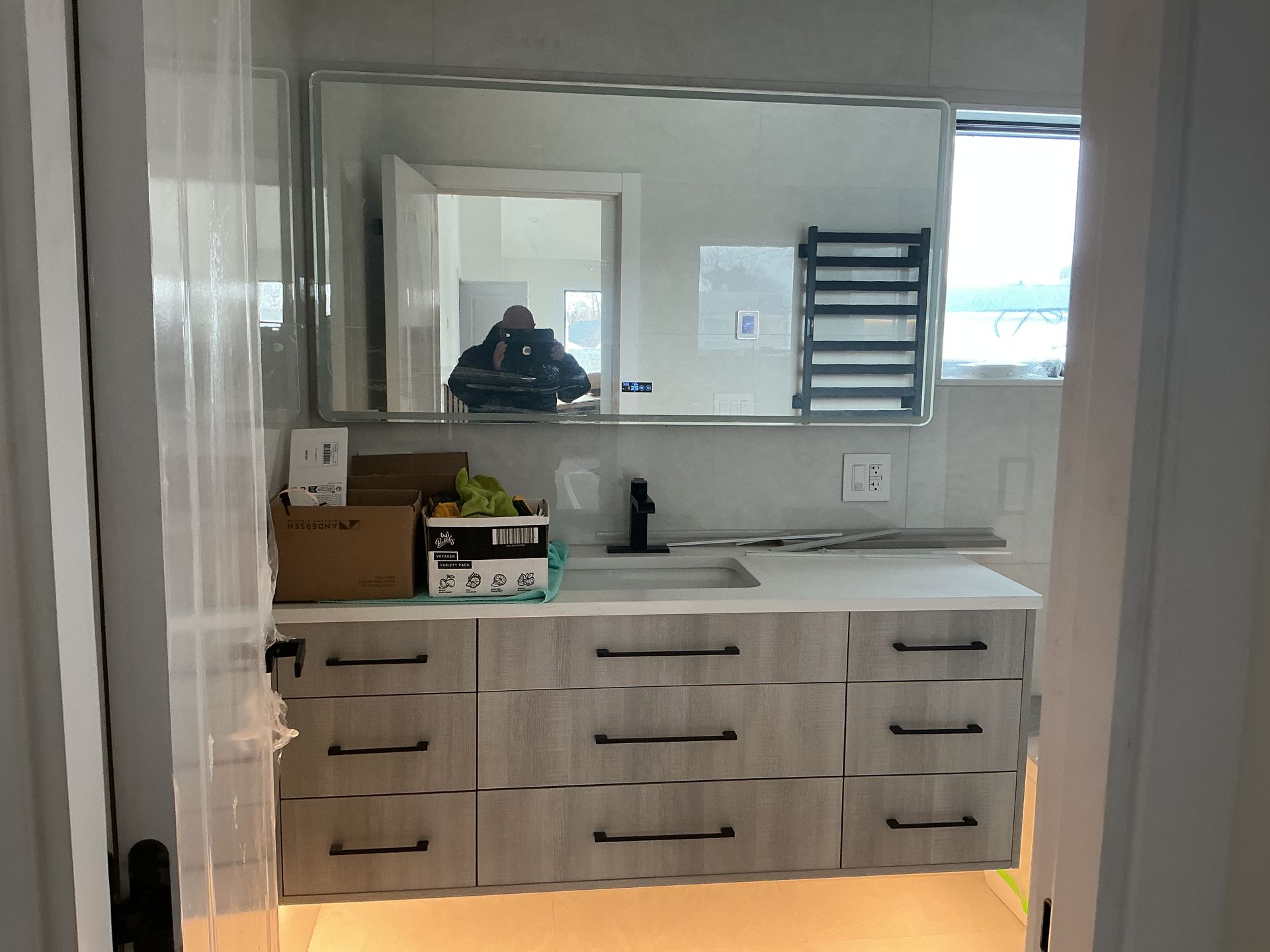 Modern bathroom vanity with double sinks, large mirror, and towel rack behind a glass shower door