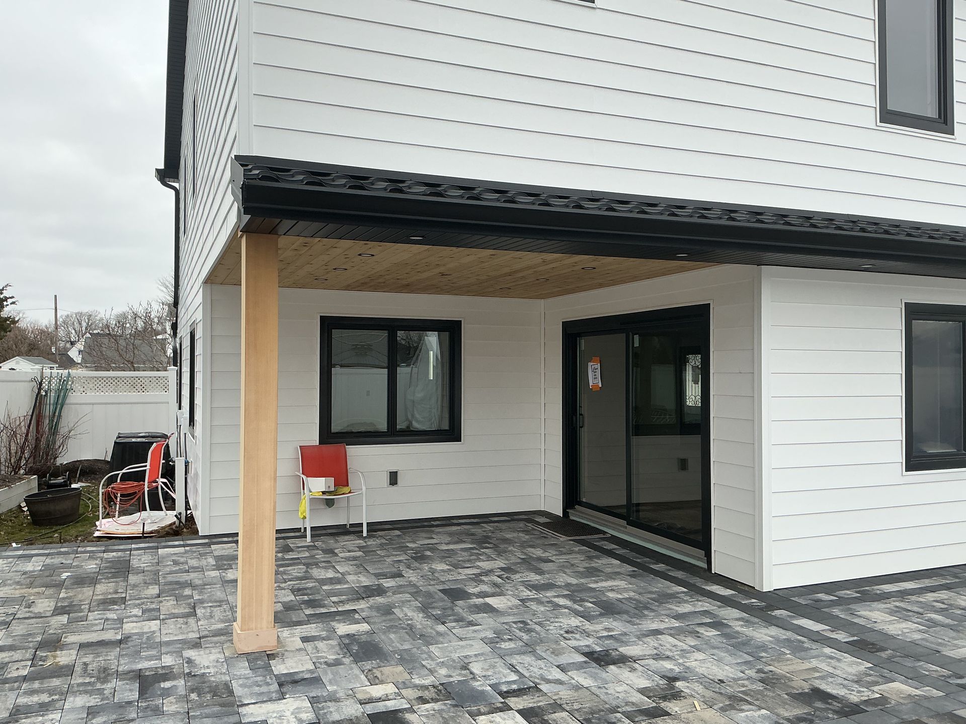 Covered patio with stone pavers, sliding glass door, and white house exterior