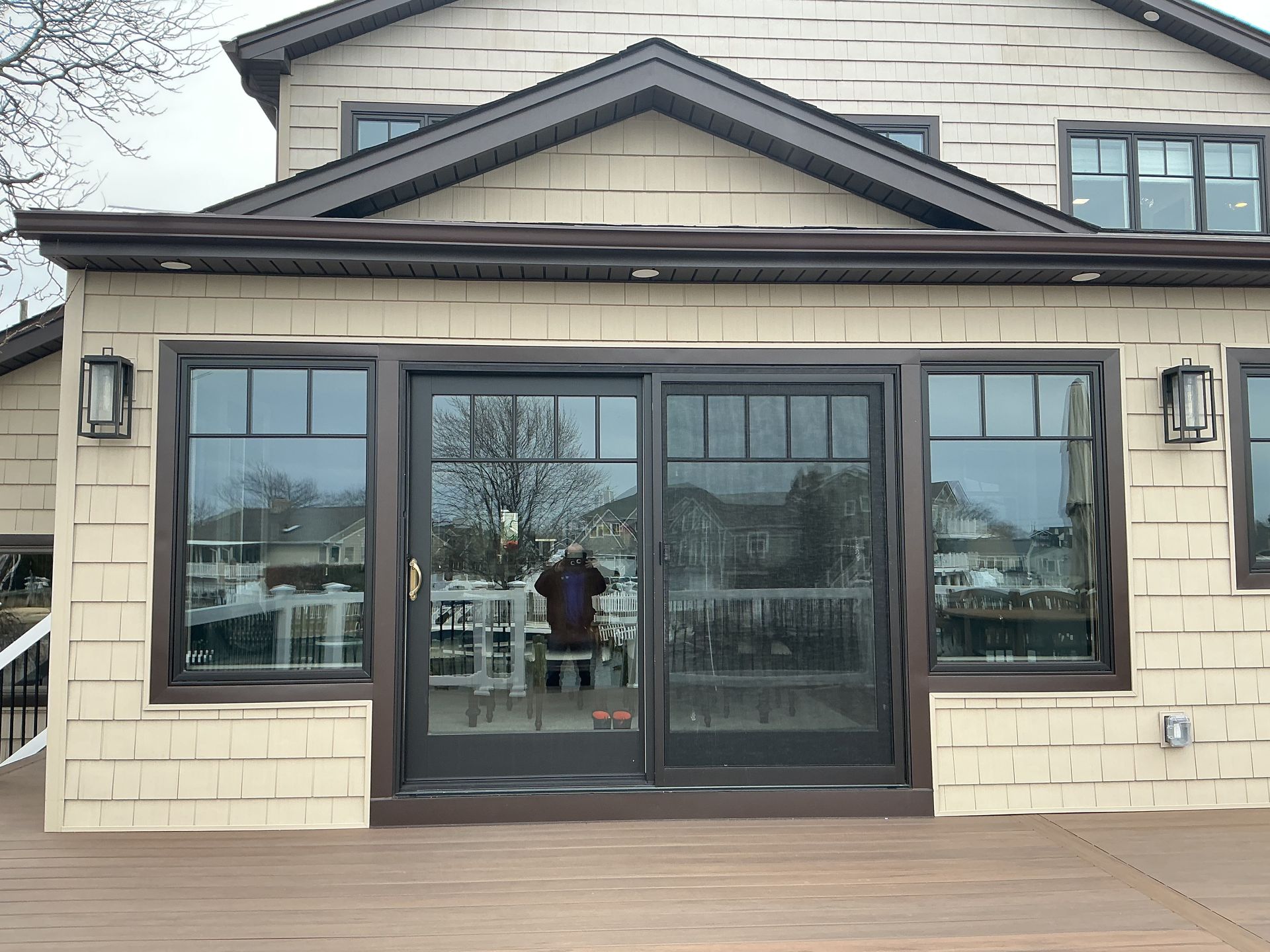 Front view of a house with beige siding and black-framed sliding glass doors under a covered patio.