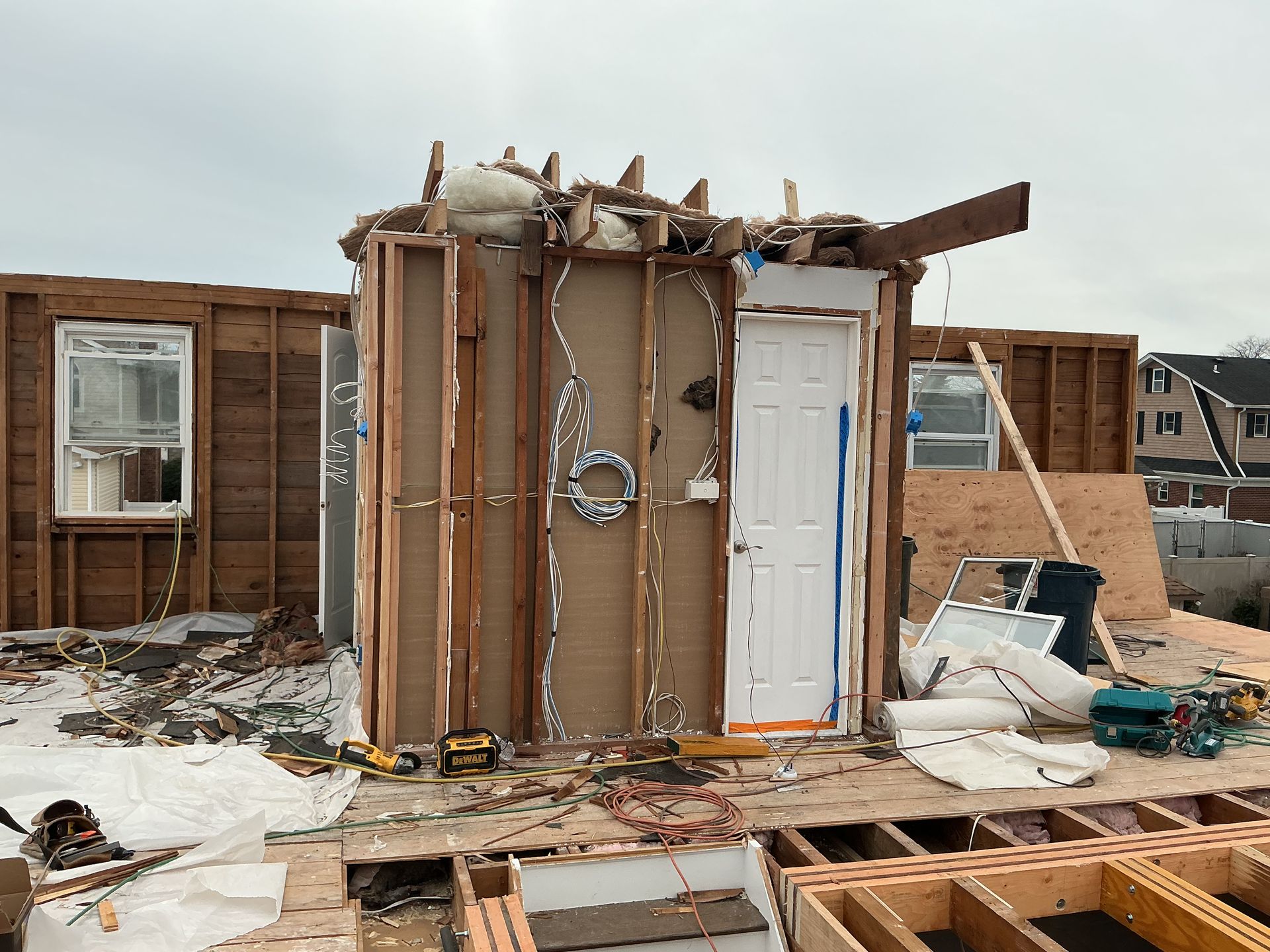 Damaged house wall and debris after storm, with a torn-off section and snow on the ground