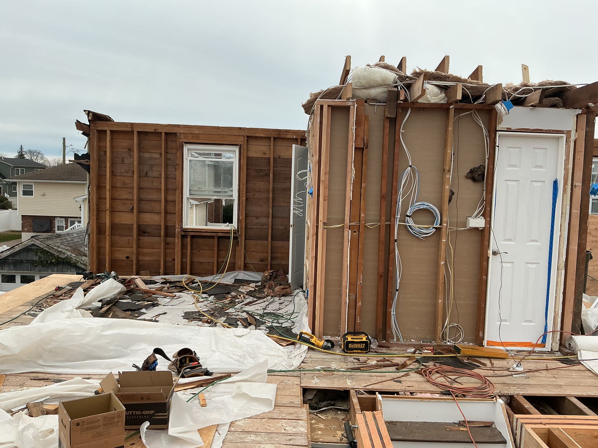 Partially demolished house with exposed framing, debris, and snow on the ground