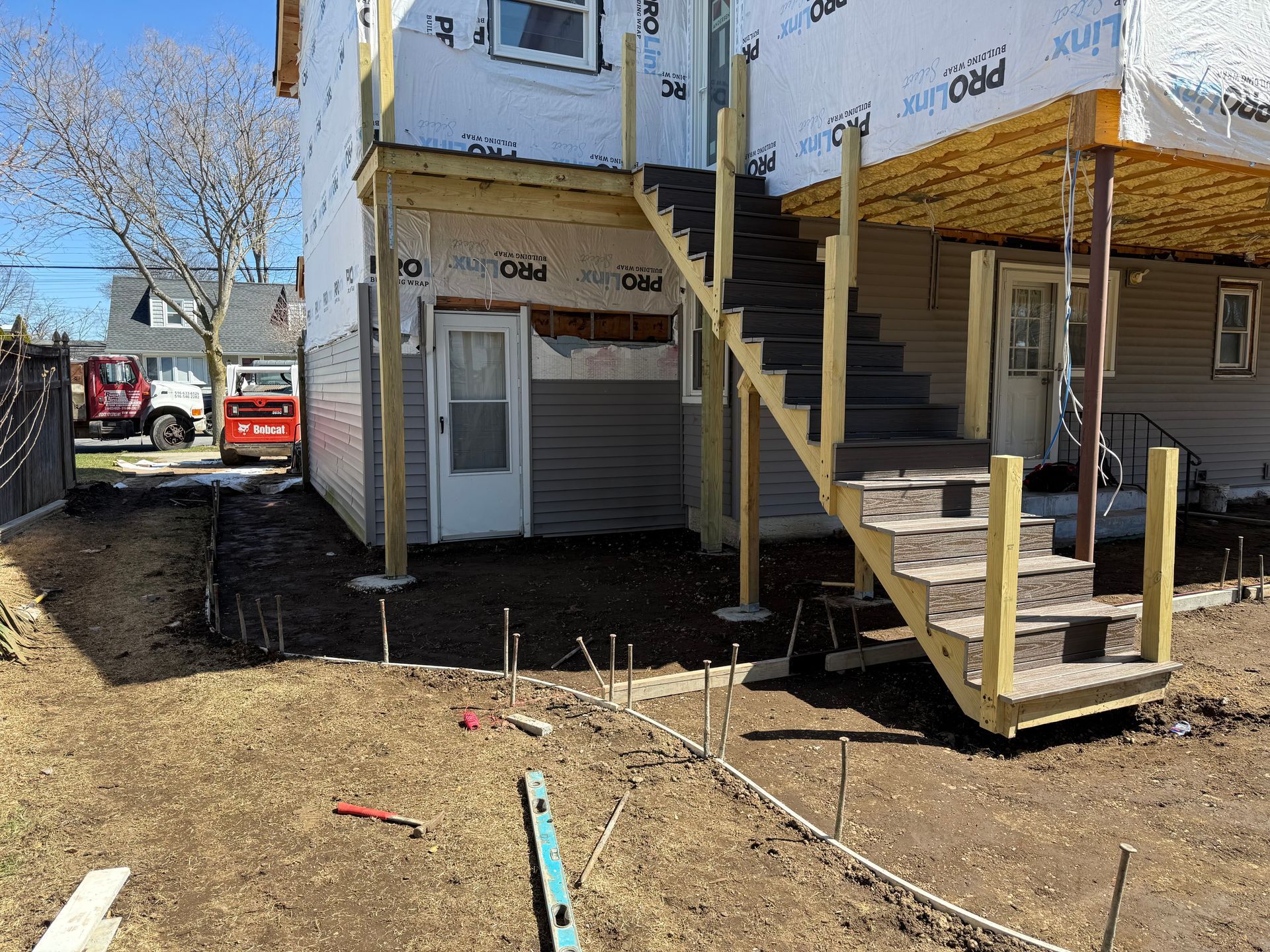 Construction site with raised house, exterior stairs, and exposed dirt ground
