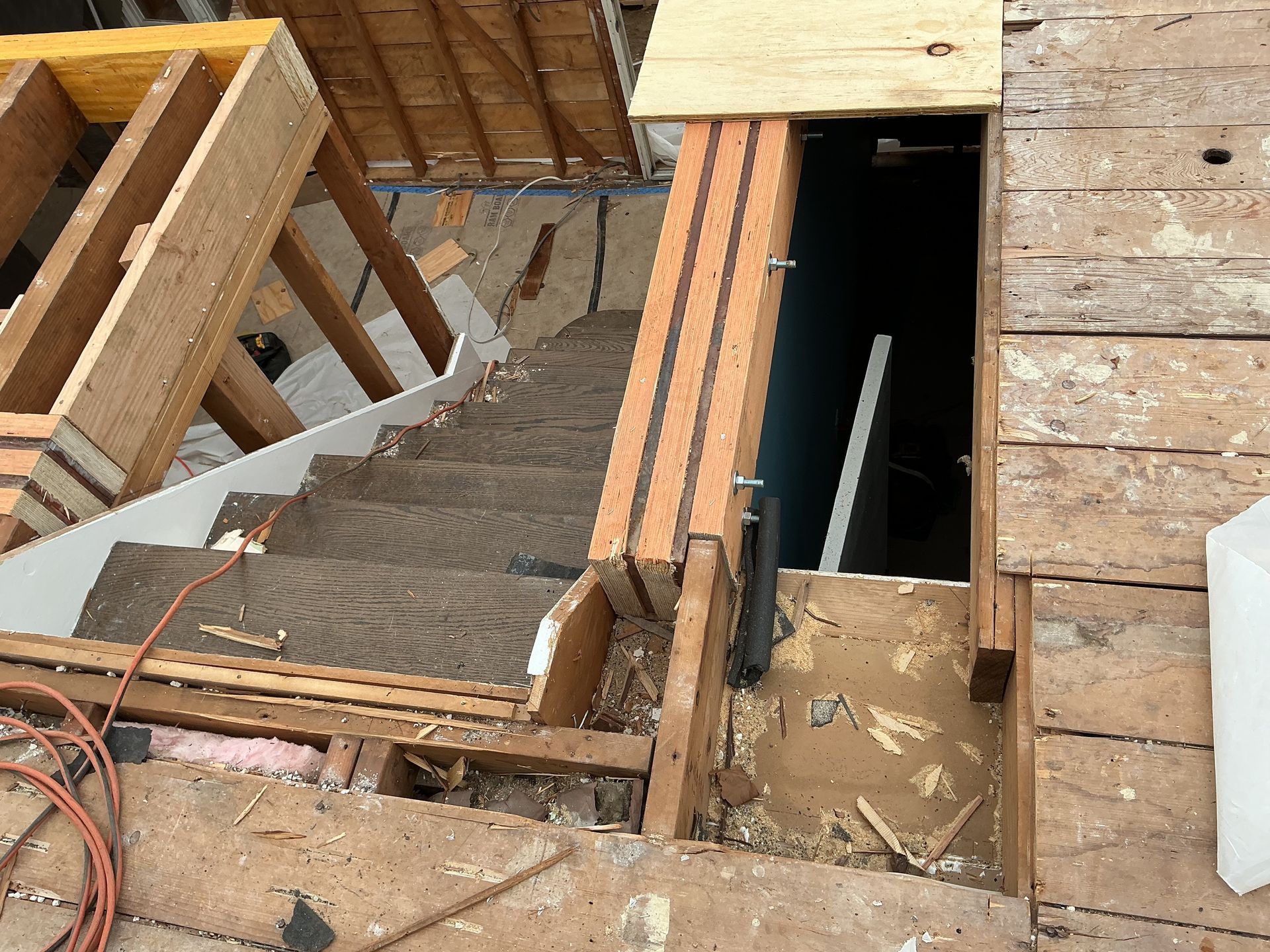 Top-down view of a construction stairwell with wooden framing and open floor joists.