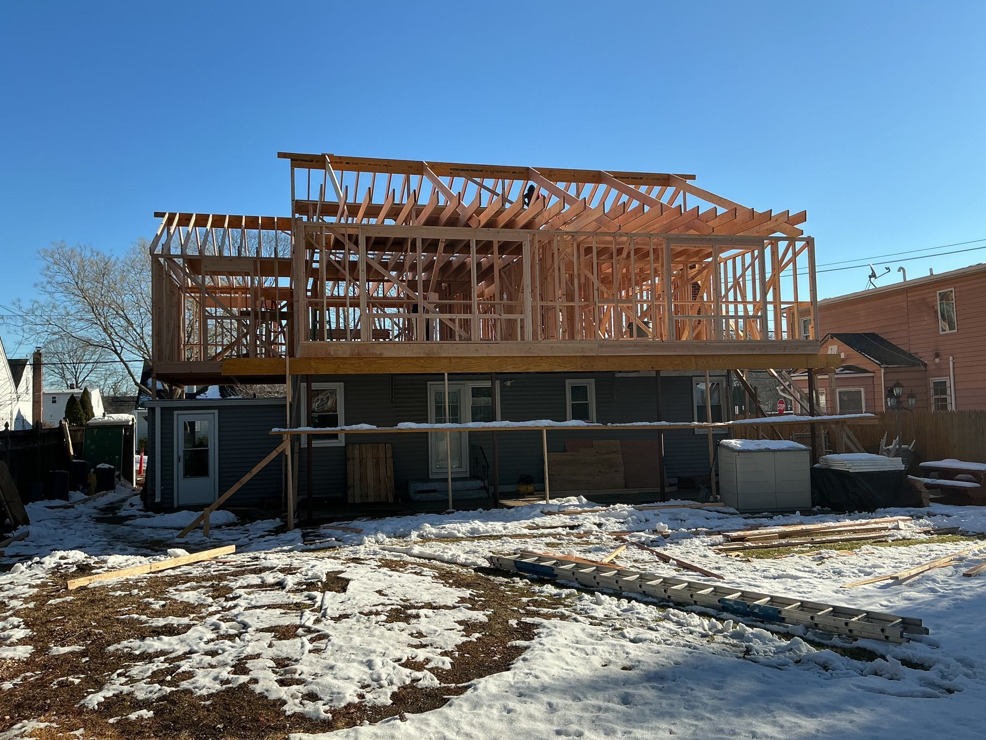 House under construction with exposed wooden framing and snow on the ground