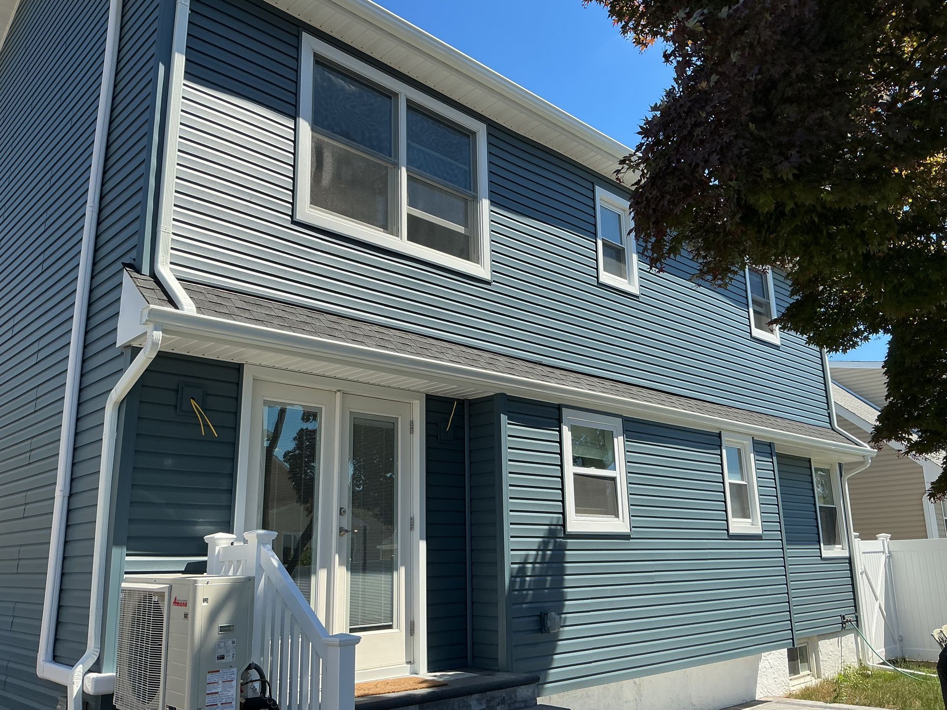 Blue two-story house with white trim and a small front porch under a clear sky