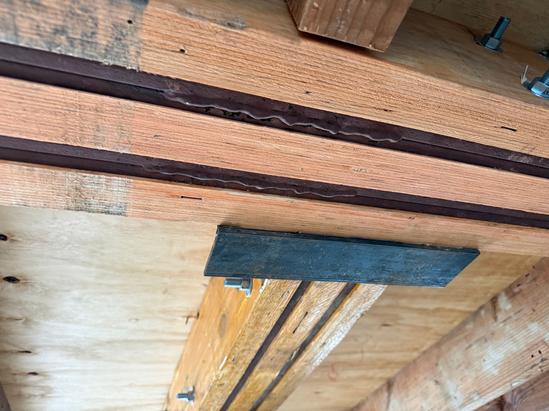 Close-up of damaged wooden beams with a dark patch and a broken board in a construction area