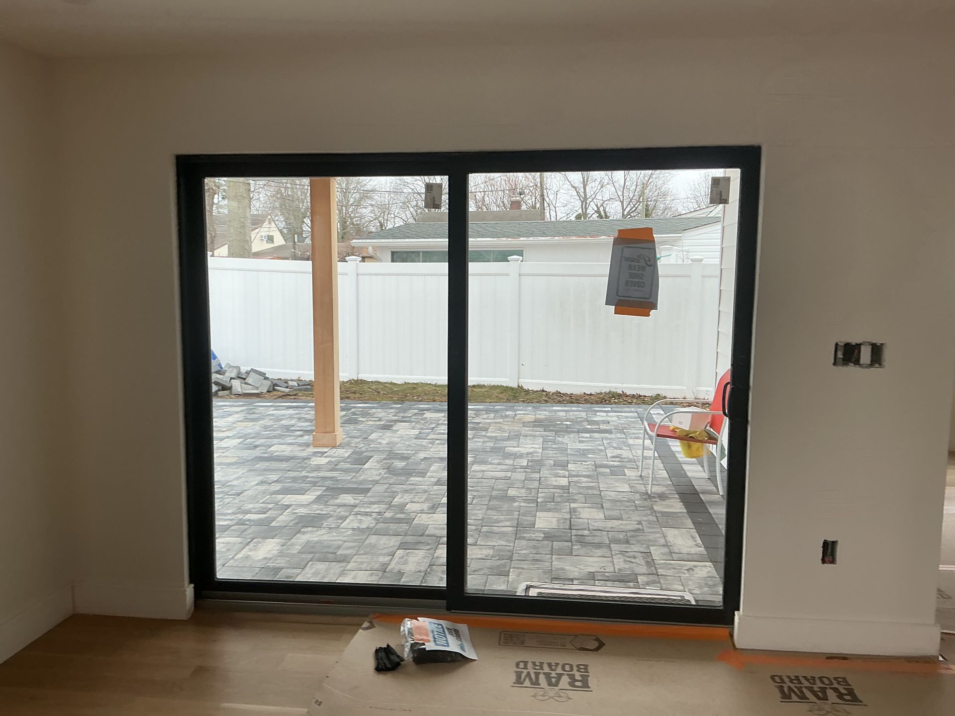 Empty room with large sliding glass doors opening to a paved backyard and white fence