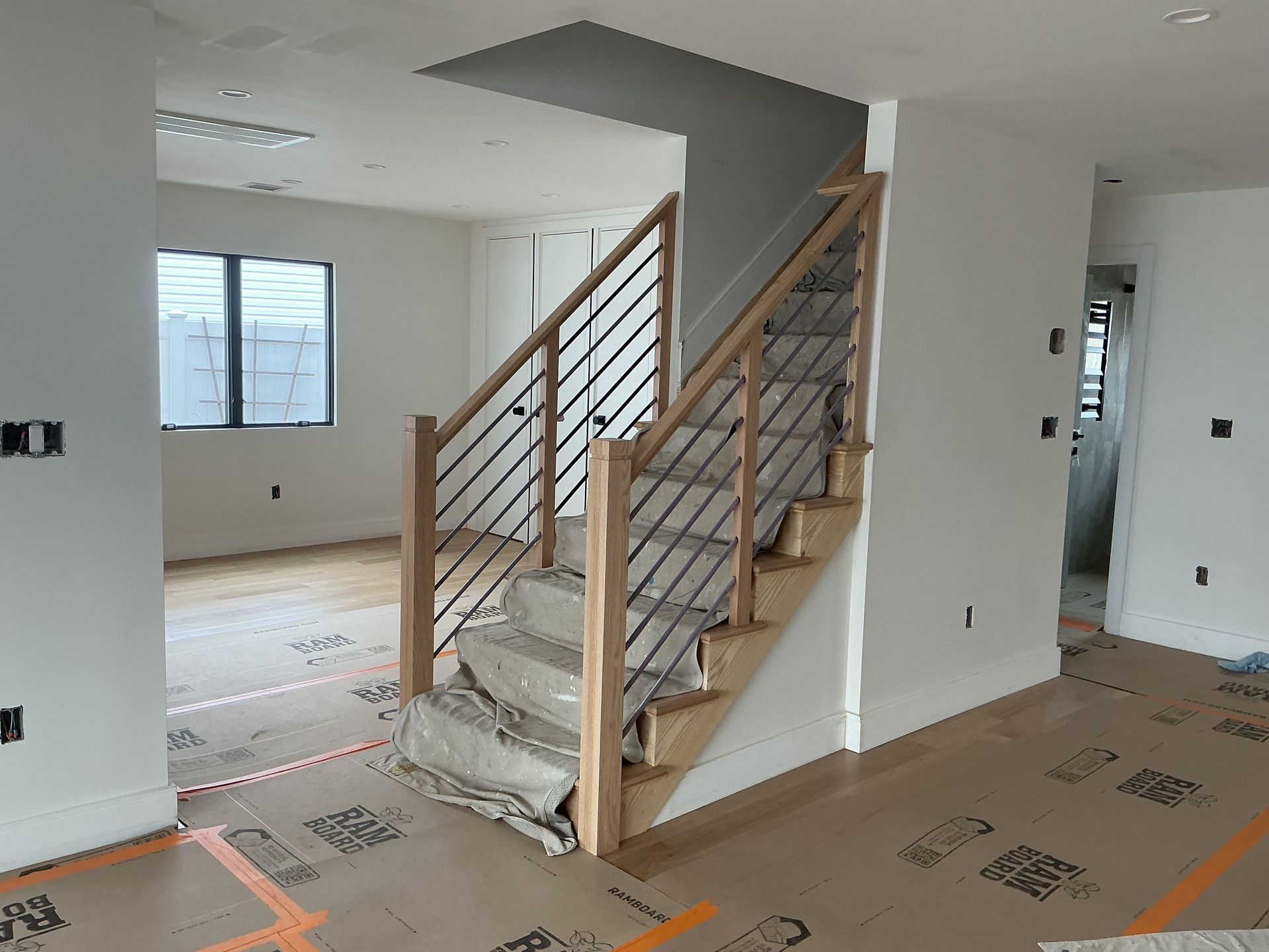 Interior staircase in a partially finished house with white walls and exposed flooring materials.