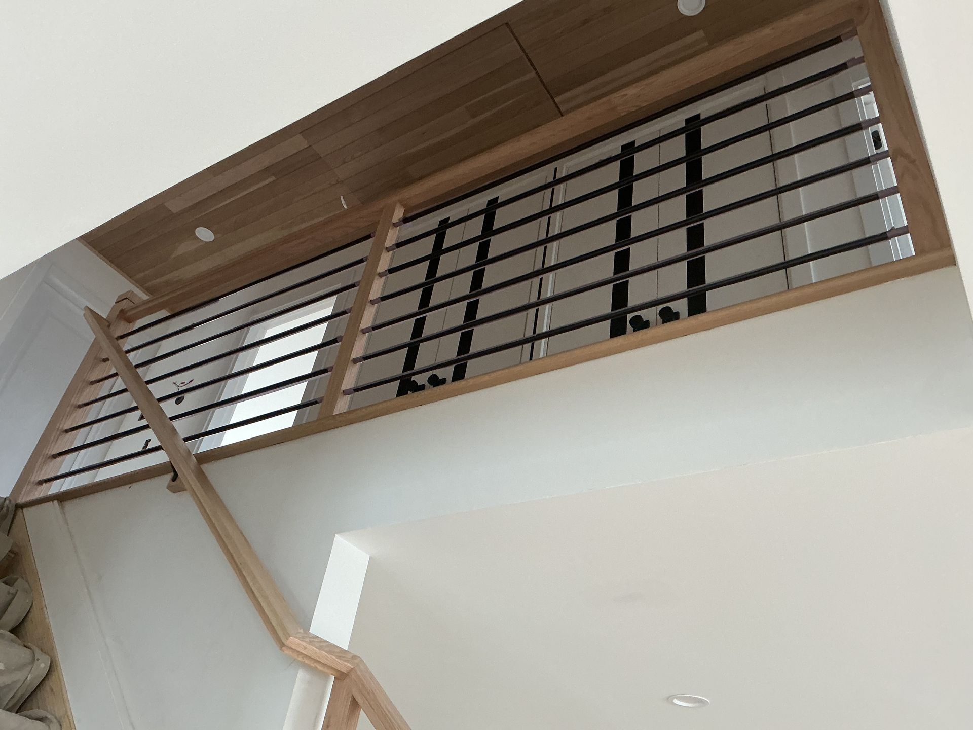 Interior staircase with wooden handrail and metal railing near a high ceiling