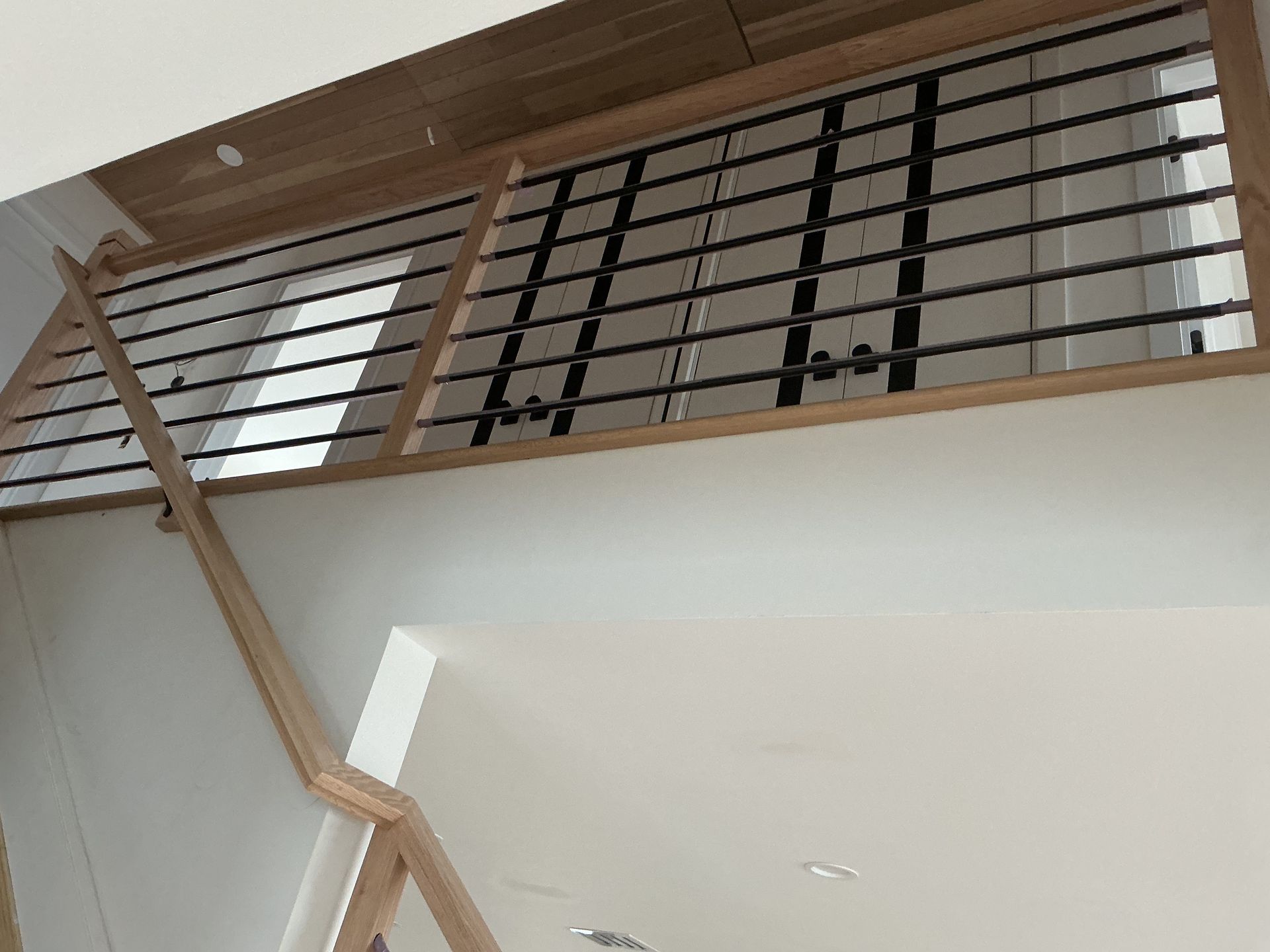 Indoor staircase with wooden railing and metal balusters in a bright modern home