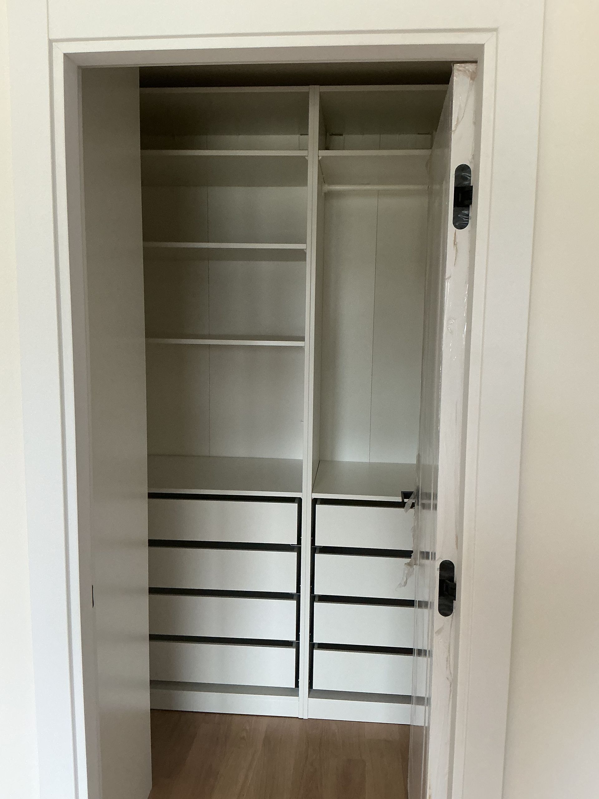 Open closet with shelves and white drawers inside a doorway