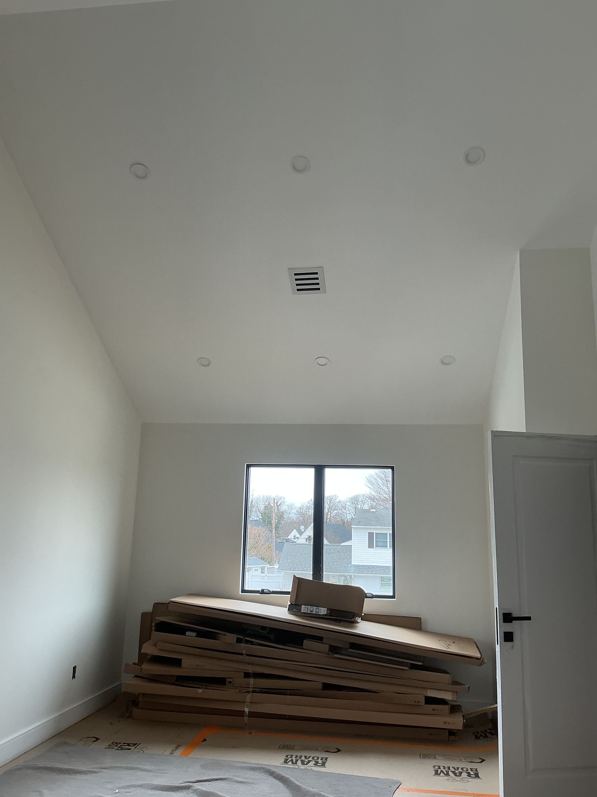 Unfinished room with stacked cardboard and a window letting in daylight.