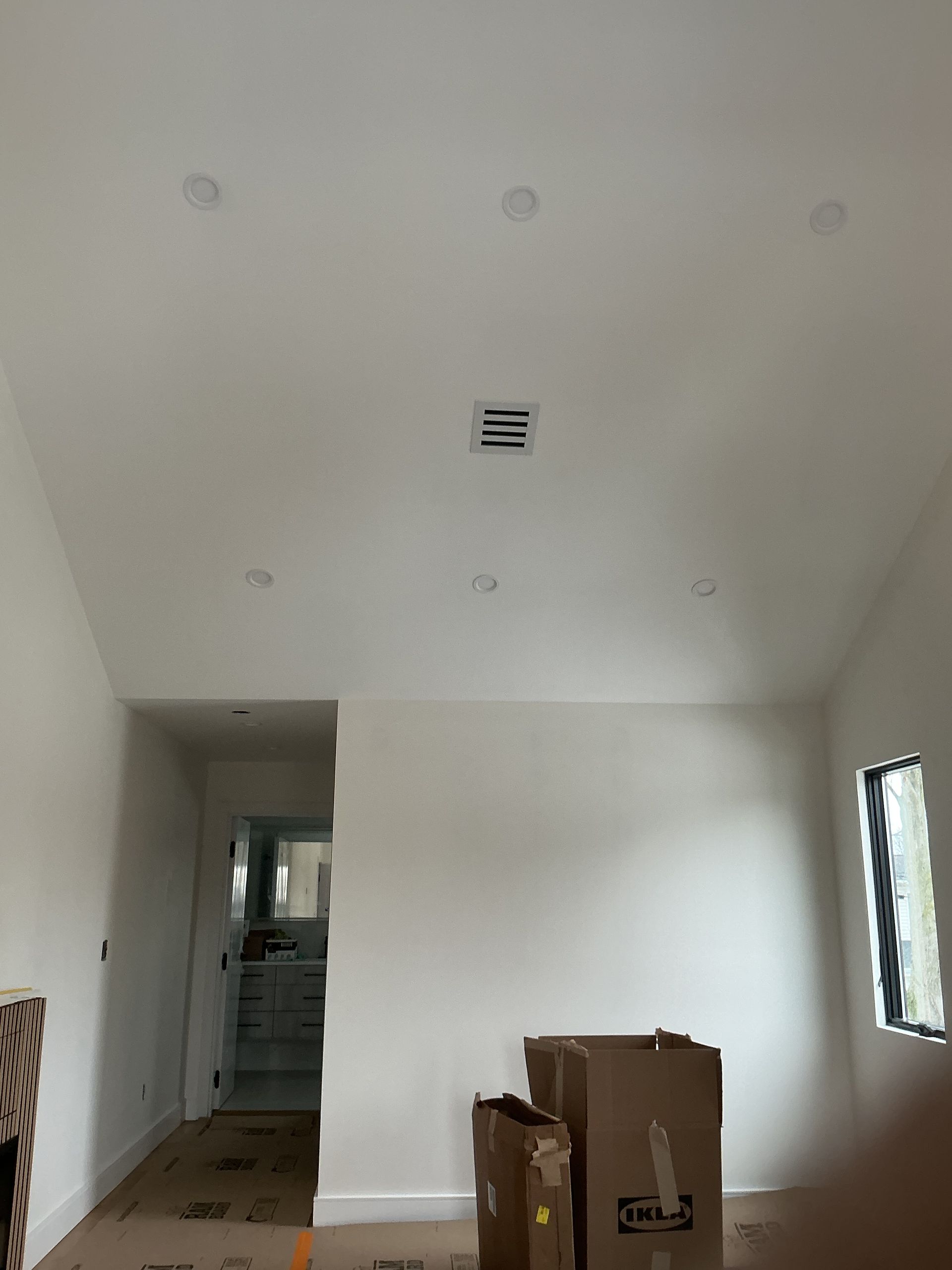 Empty white room under construction with boxes on the floor and a window on the right.