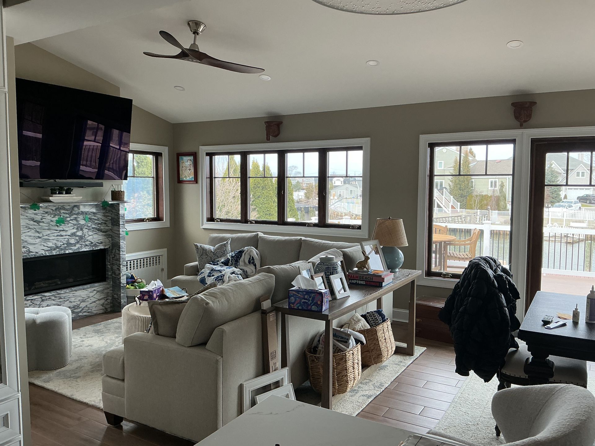 Bright living room with beige sofa, TV, large windows, and dining table by sliding glass doors.