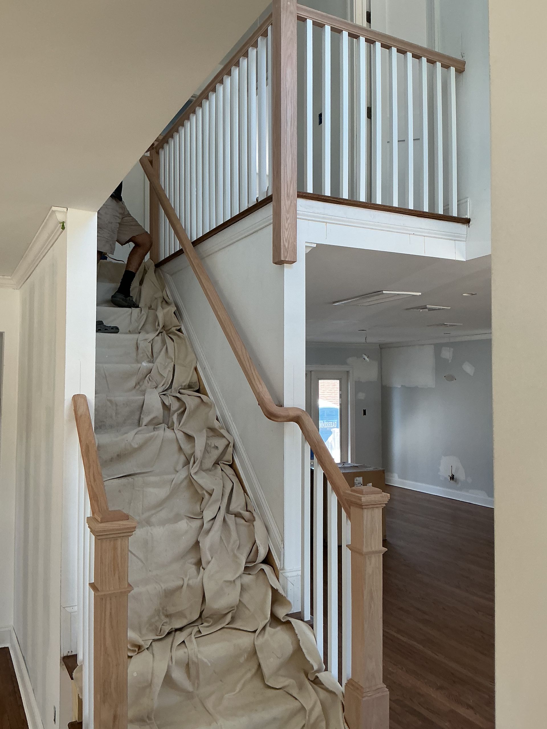 Staircase covered with protective plastic sheeting in an unfinished home interior.