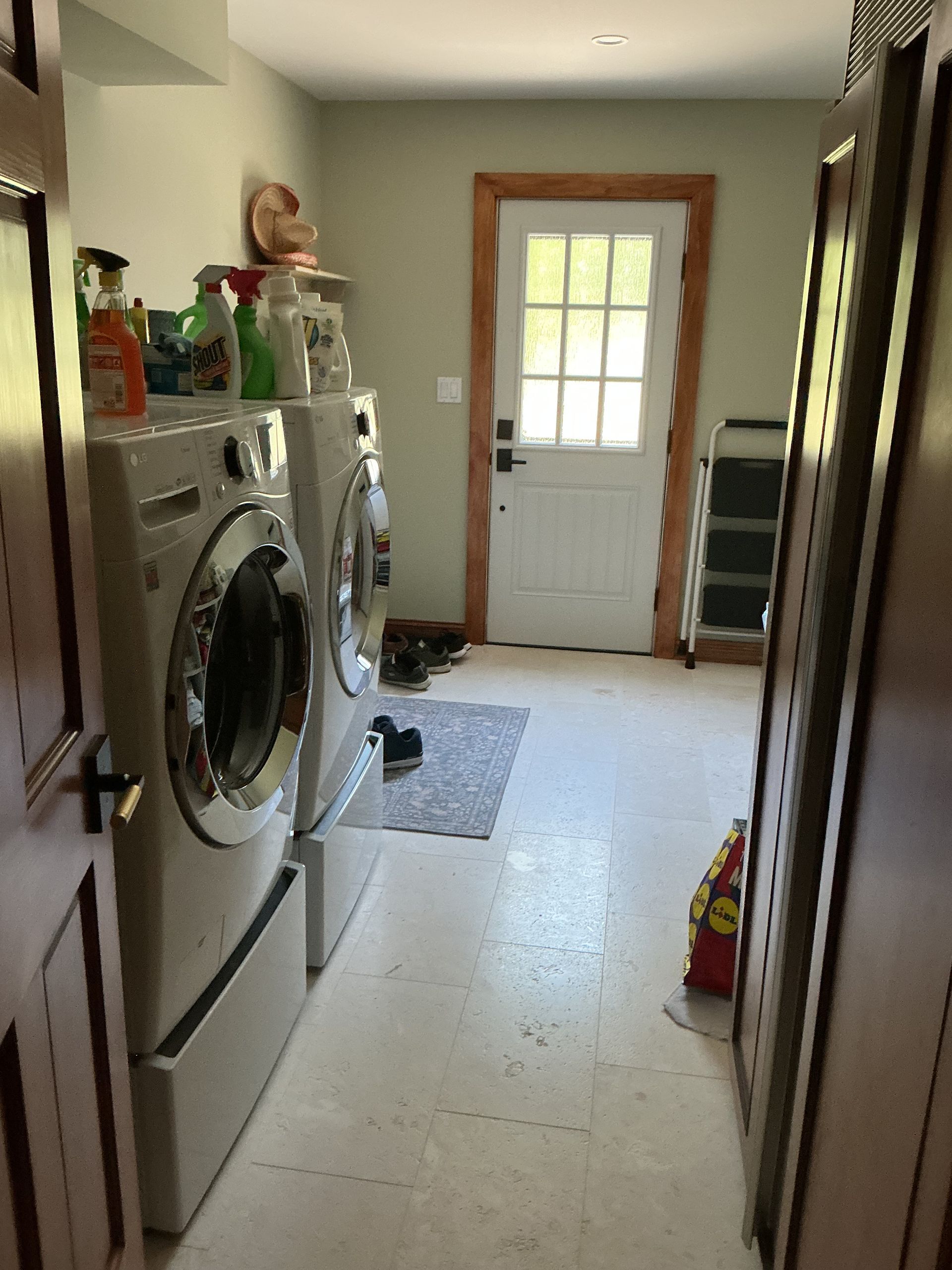 Laundry room hallway with washer and dryer on the left and a door at the end.