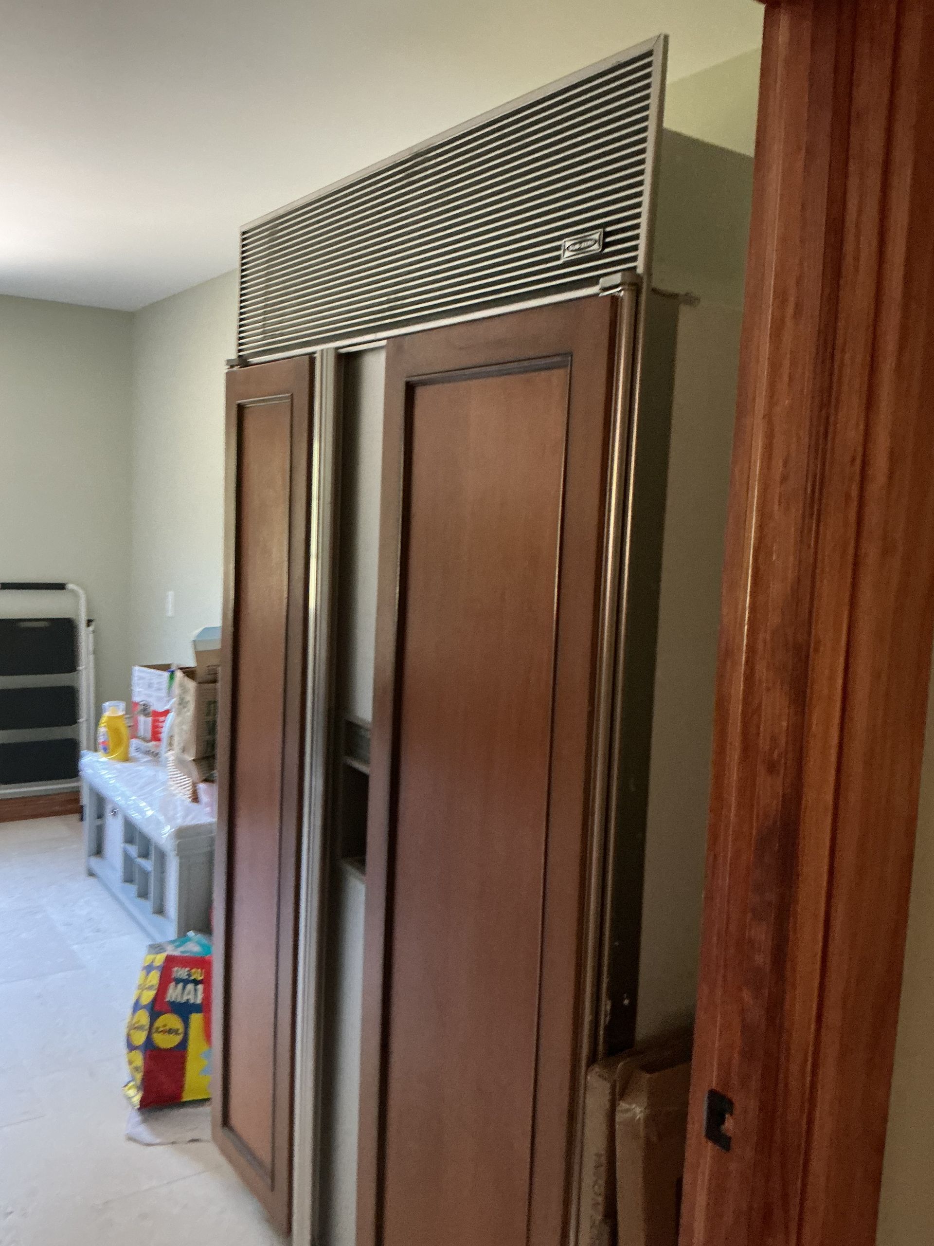 Wooden wardrobe doors in a bedroom, with a shelf and items visible beside it.