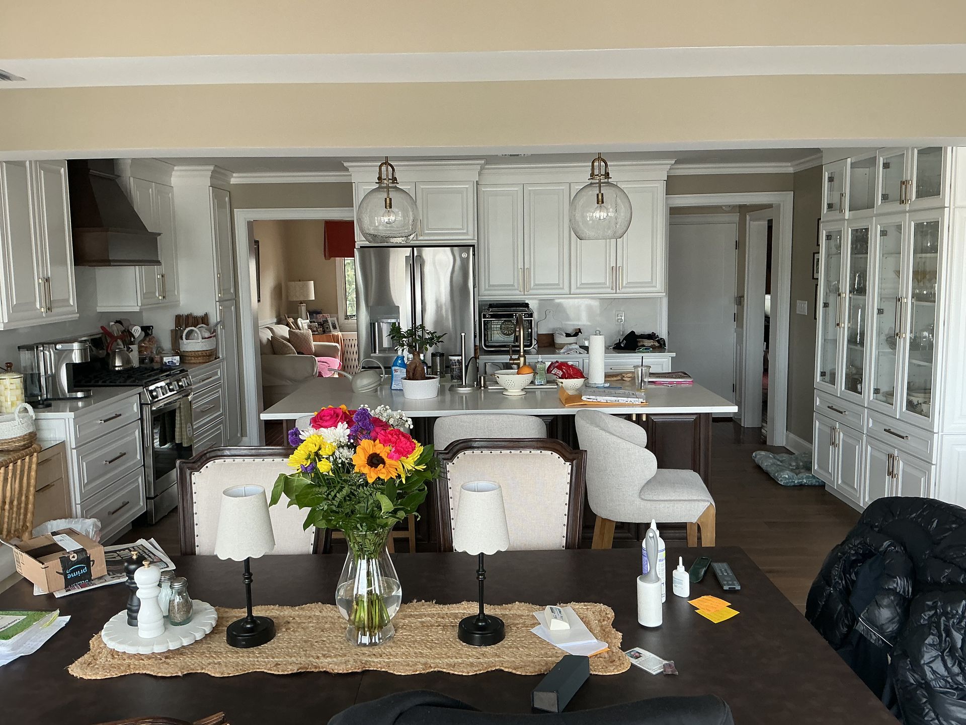 Bright open kitchen and dining area with white cabinetry, island, flowers, and dark wood floors
