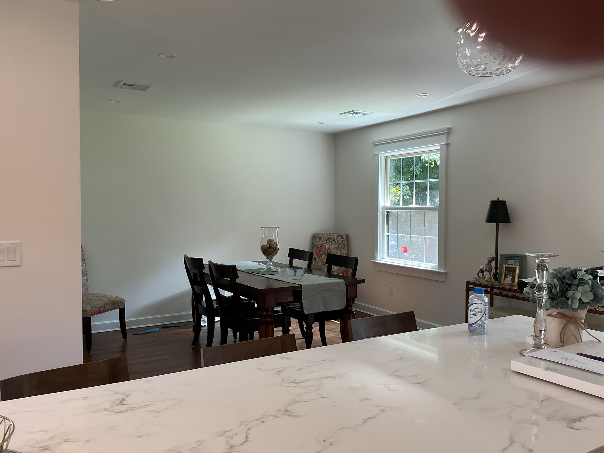 Dining area with dark wood table, white walls, and a window letting in natural light
