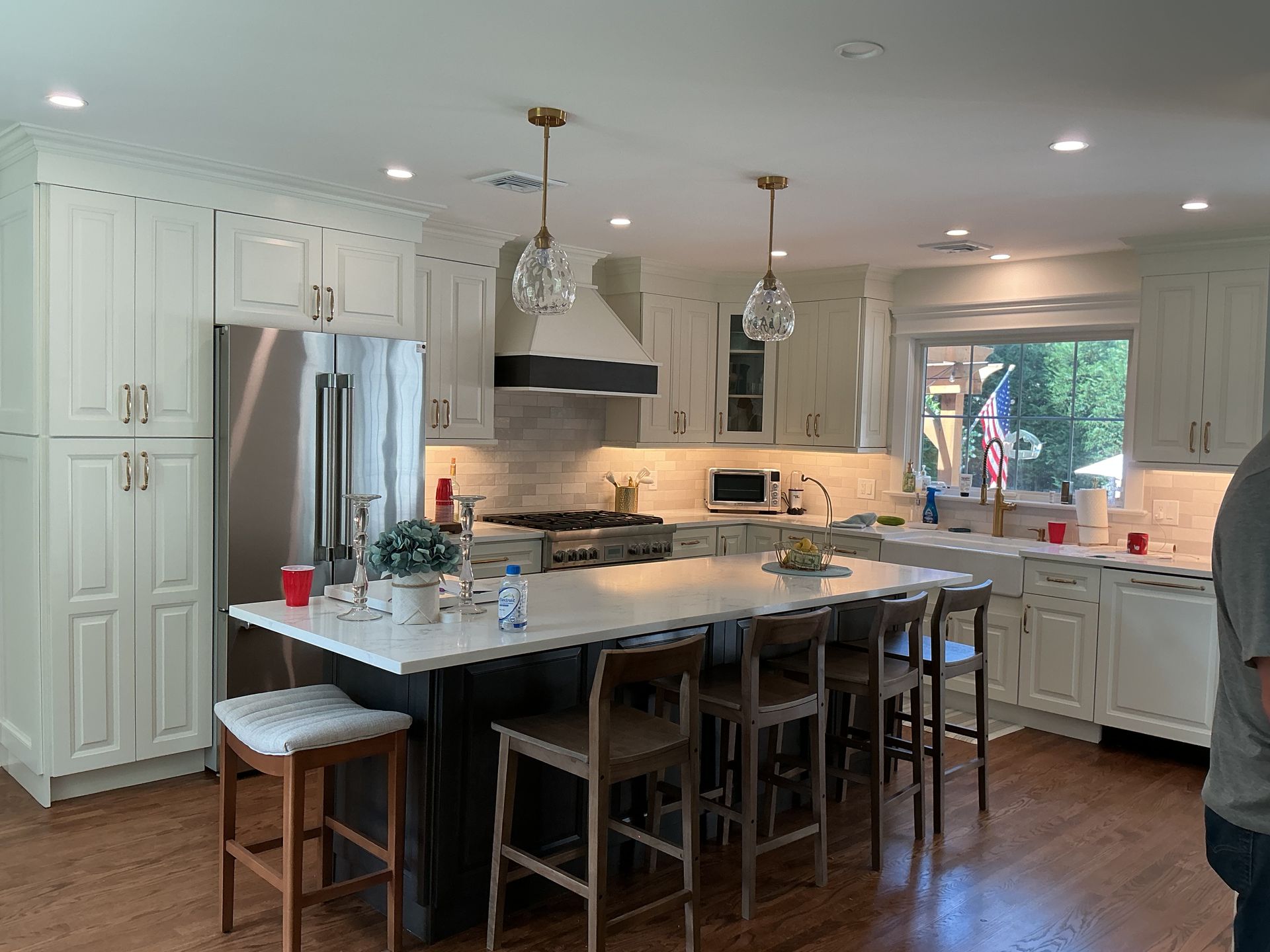 Bright modern kitchen with white cabinets, granite island, stools, and a stainless steel fridge