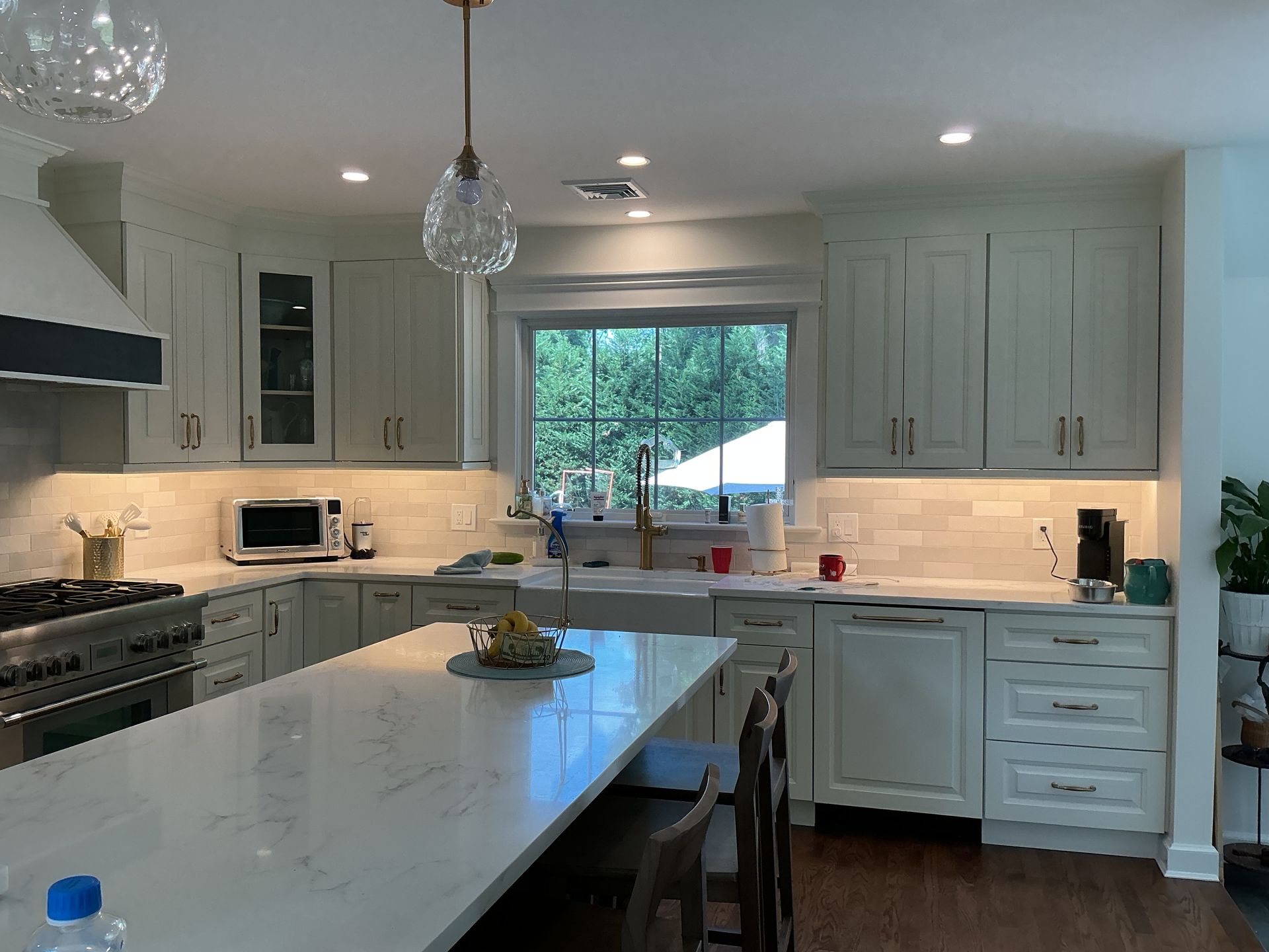 Bright white modern kitchen with island, pendant lights, and a window over the sink