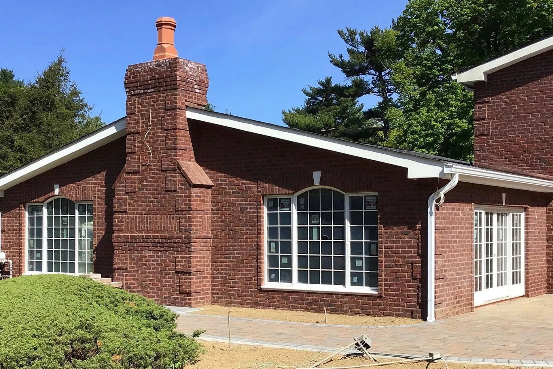 Brick building with white-framed windows, brick chimney, and white trim against a blue sky.