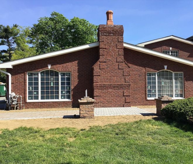 Brick building with white-framed windows, brick chimney, and green grass in the foreground.