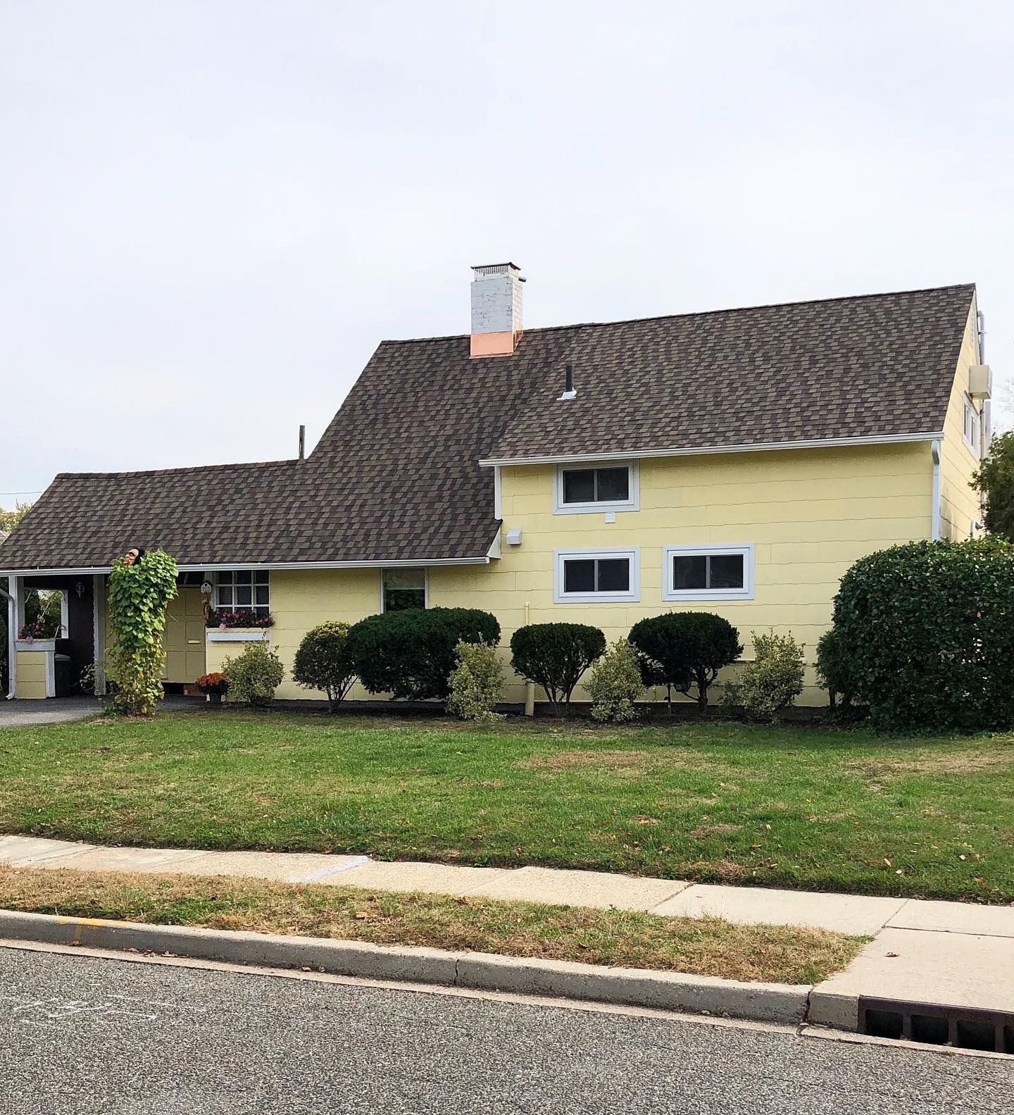 Yellow house with brown roof and green lawn.