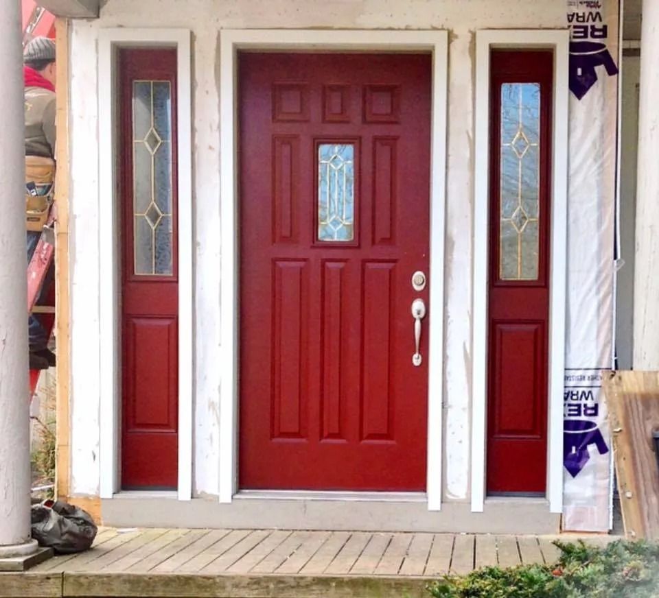 Red front door with sidelights, white trim, and a porch.