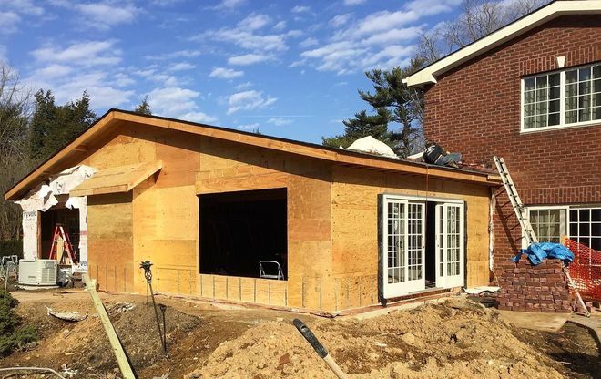 Construction site with a partially built extension next to a brick house.